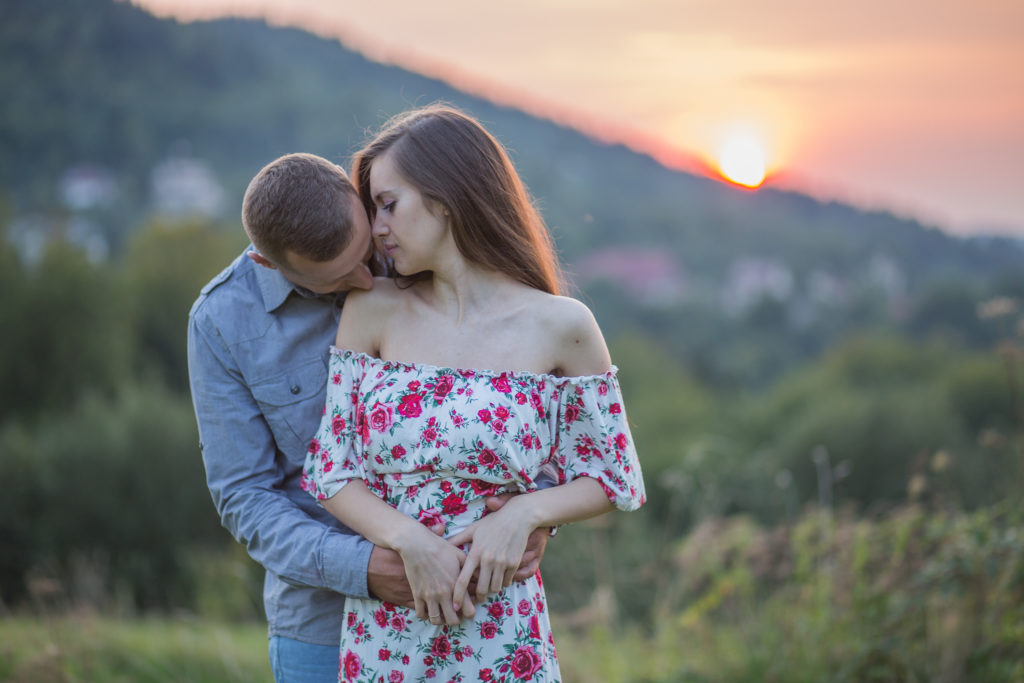 mężczyzna całuję kobietę w ramię przy zachodzie słońca, katarzynapaciorek.pl
