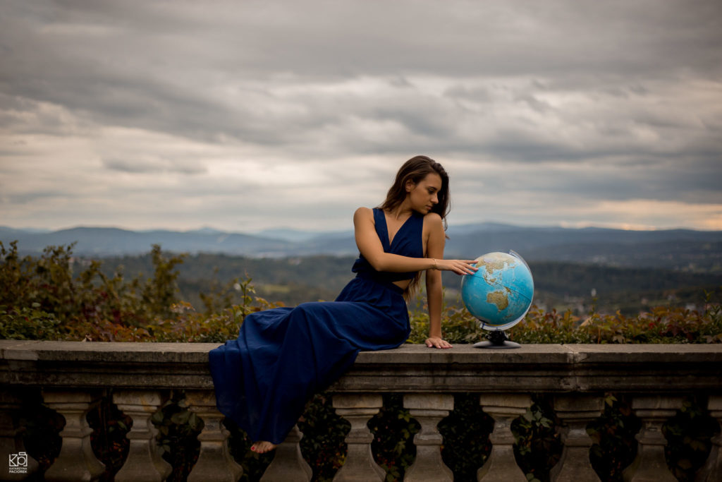Kobieta w niebieskiej sukni patrzy na globus, sesja kobieca