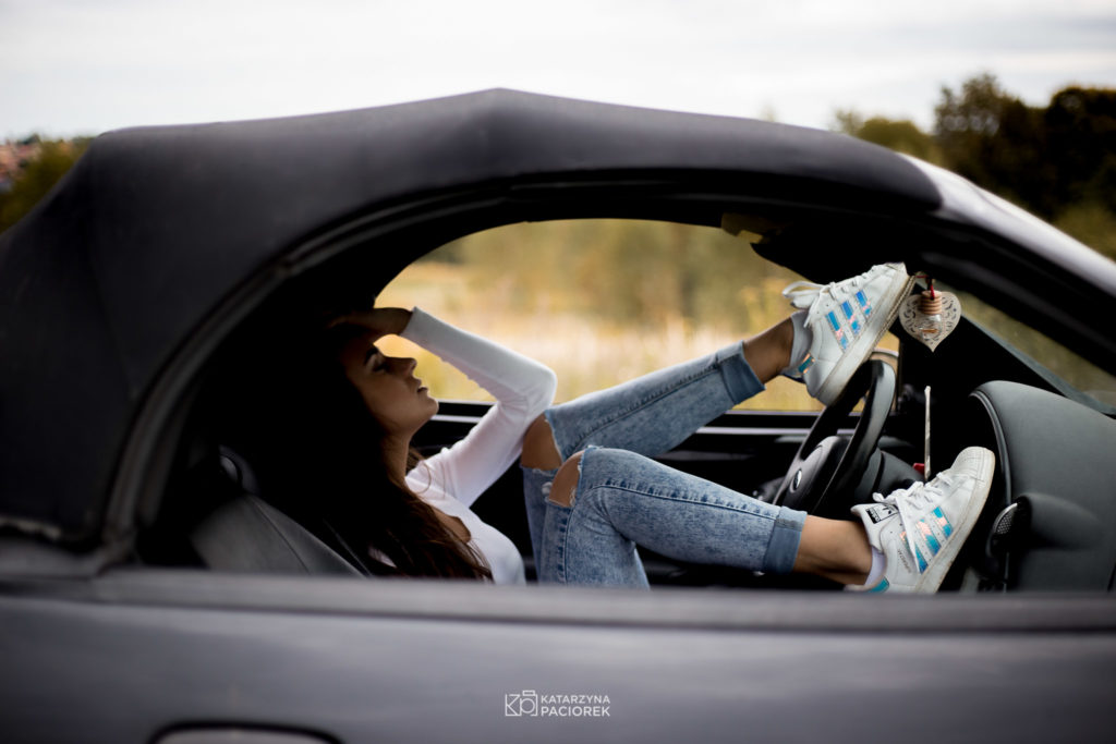 Kobieta odchylona na siedzeniu w samochodzie, trzymająca nogi na kierownicy