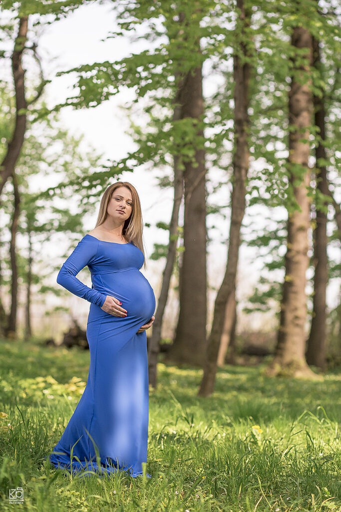 Sesja ciążowa, kobieta w długiej niebieskiej w sukni, w lesie