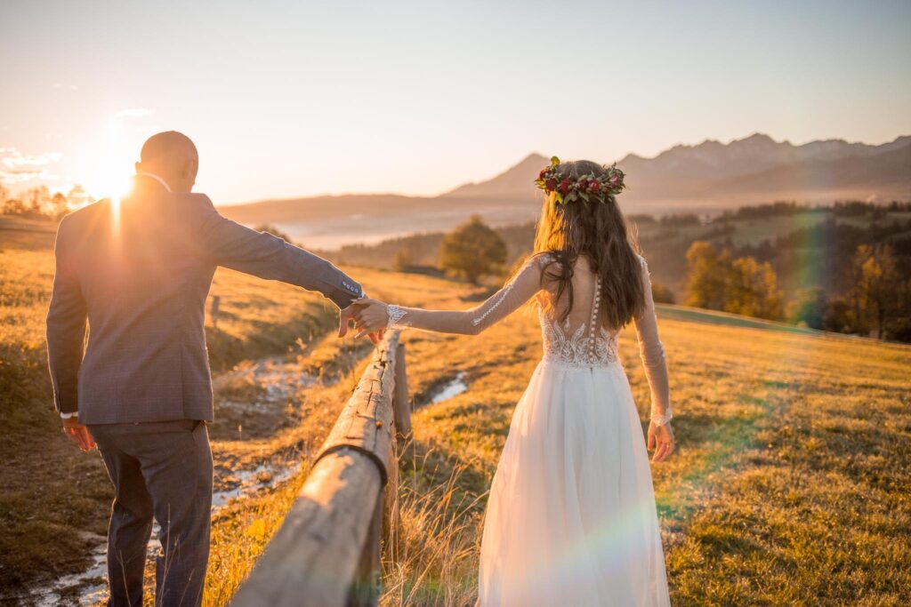 Zdjęcie przedstawia kobietę i mężczyznę w strojach ślubnych. Wyciągają do siebie rękę.