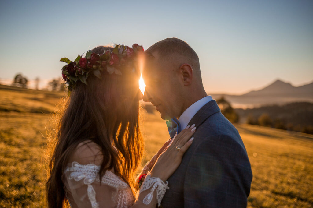 Zdjęcie przedstawia tulące się małżeństwo. Między ich głowami przedostają się promienie słońca