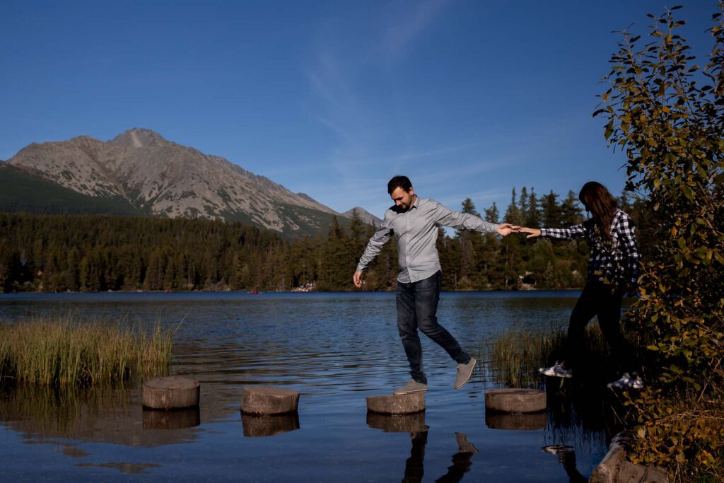 kobieta i mężczyzna idący po drewnianych balach umieszczonych w jeziorze